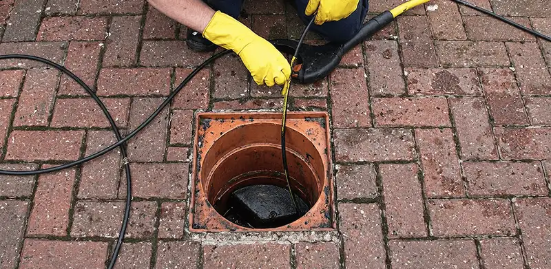 Drain cleaning technician using a drain snake to clear a clogged drain in Aurora, IL