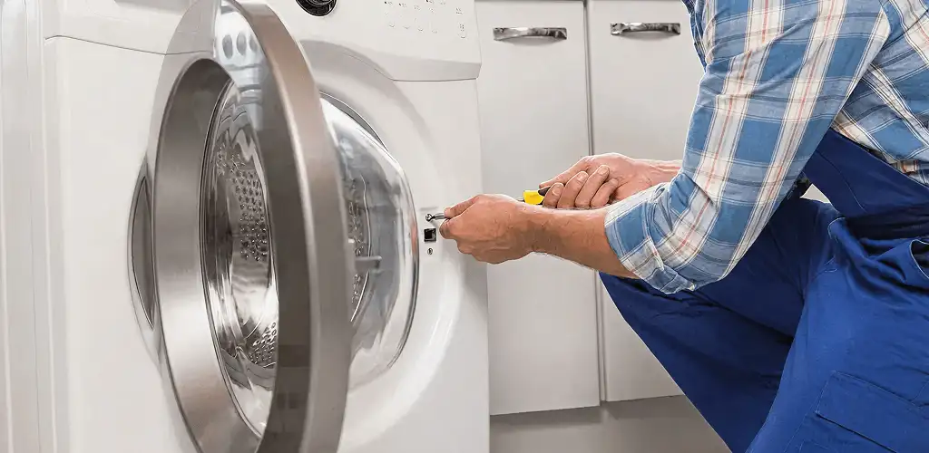Handyman repairing a clothes dryer and checking electrical connections in Aurora, IL