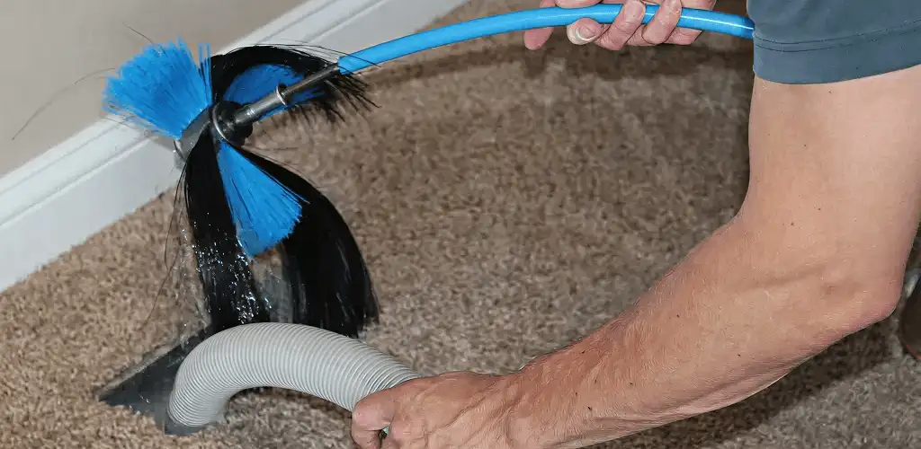 Dryer vent cleaning technician brushing lint from a vent line in Aurora, IL