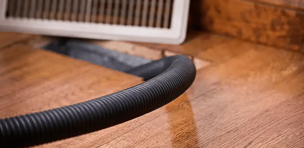 Air duct cleaning hose inserted into a floor vent for ductwork cleaning in Aurora, IL