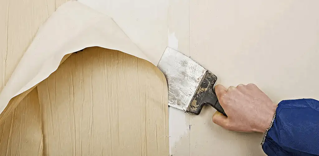 Handyman removing wallpaper with a scraper for wall preparation in Aurora, IL