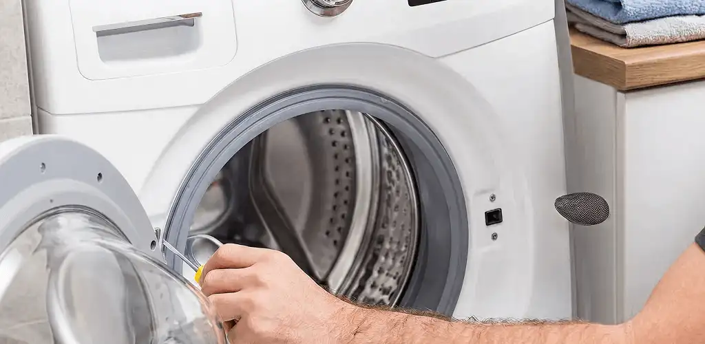 Handyman repairing a front-load washing machine and inspecting the drum in Aurora, IL