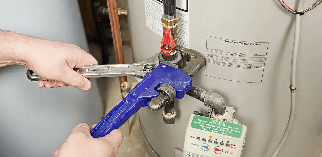 Water heater repair technician tightening the shutoff valve and supply line in Aurora, IL
